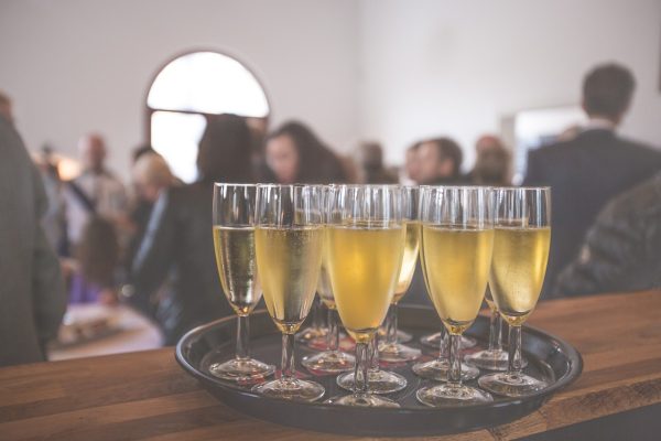 Photo of champagne glasses on a tray with people mingling in the bckground