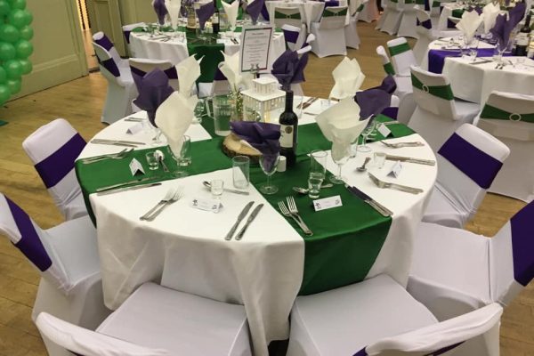Photo of table set out for a wedding with glasses, cutlery and centre piece